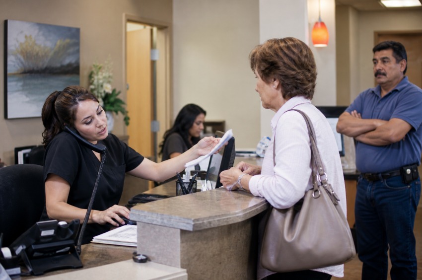 Overwhelmed receptionist managing phone calls and in-person clients
